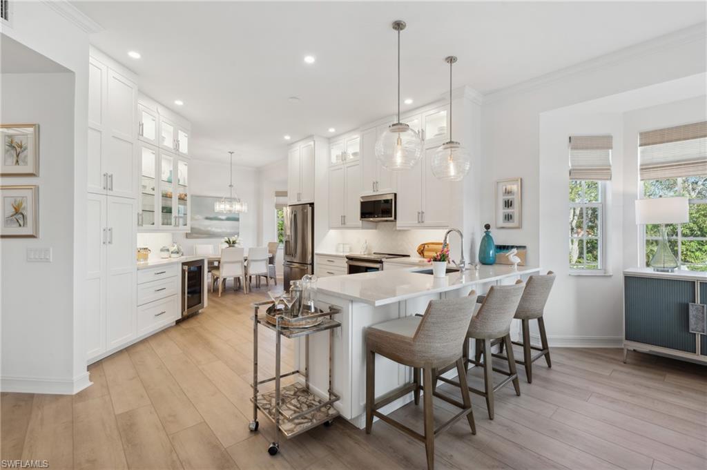 a view of a dining room and livingroom with furniture wooden floor a rug a flat screen tv a painting and a chandelier