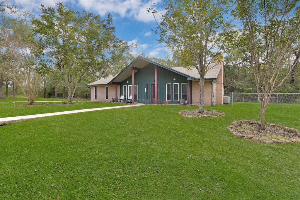 a brick house with a big yard and large trees