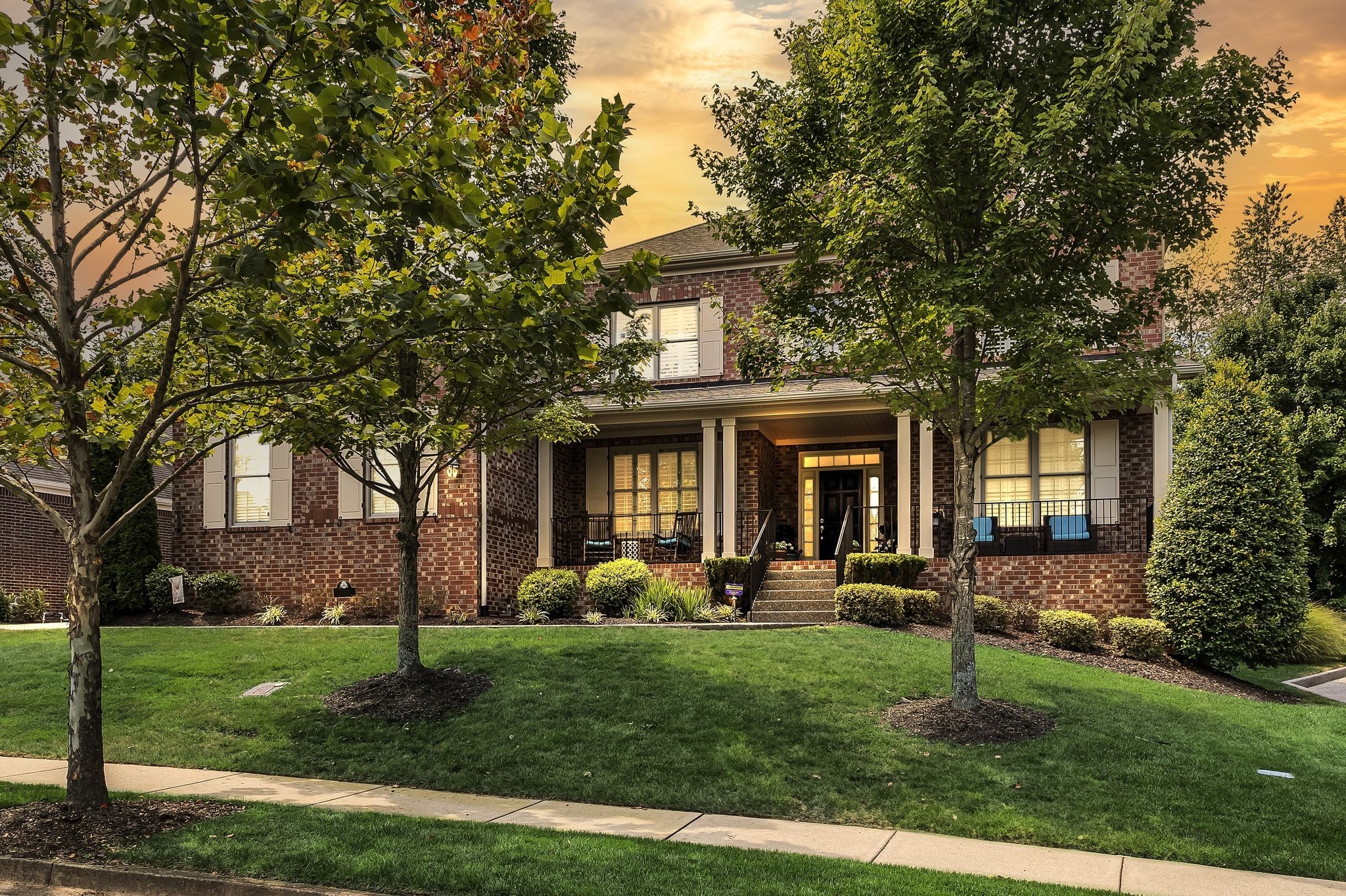 a front view of a house with a garden and trees