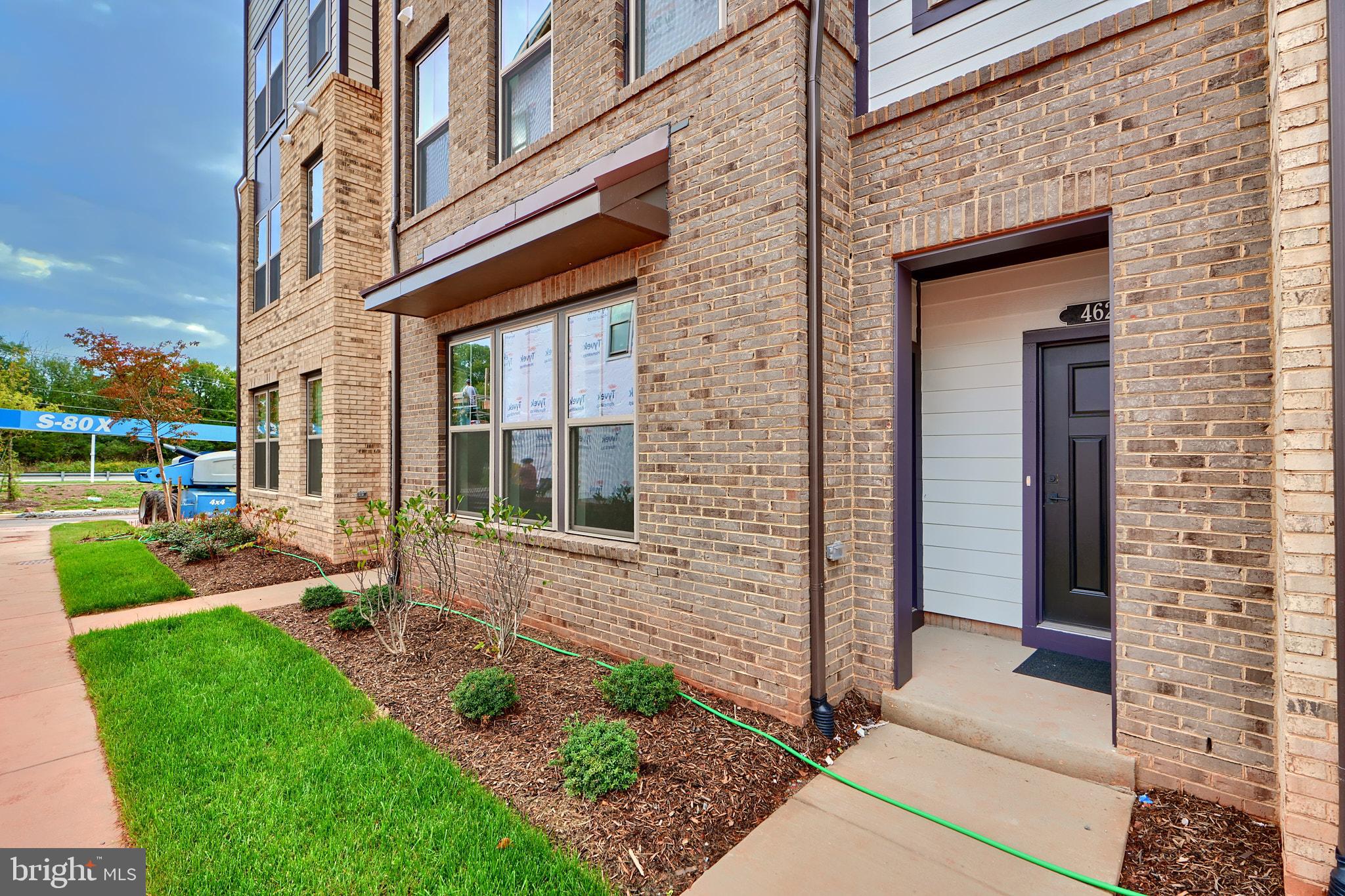 a view of a brick house with a large windows and a yard with plants