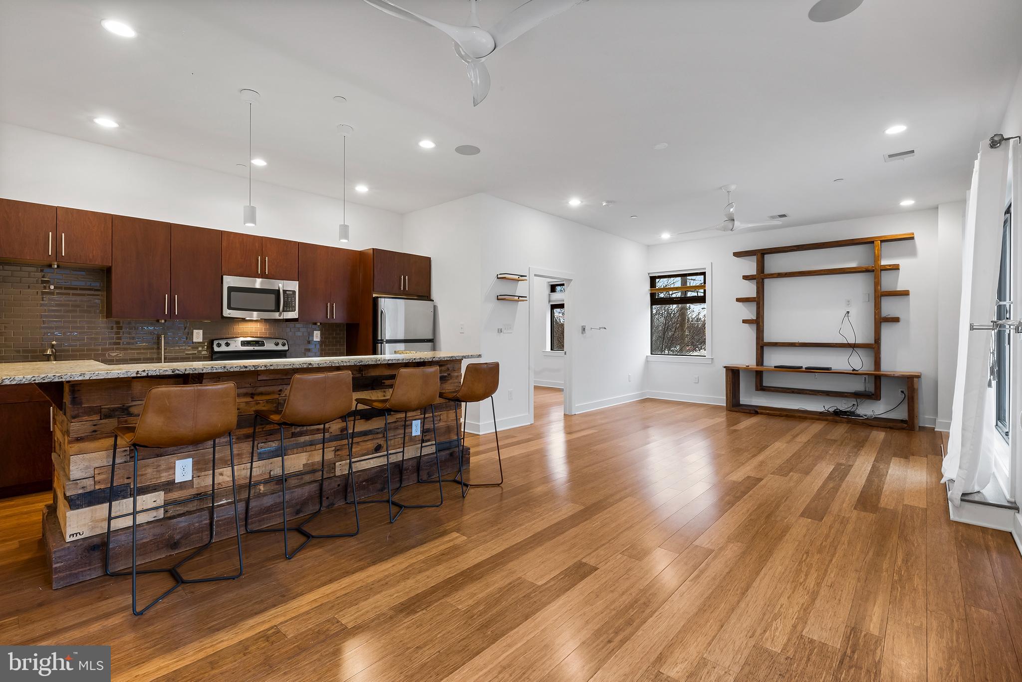 a living room with stainless steel appliances furniture and a wooden floor