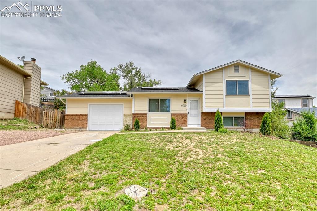 Split level home featuring a garage and a front lawn