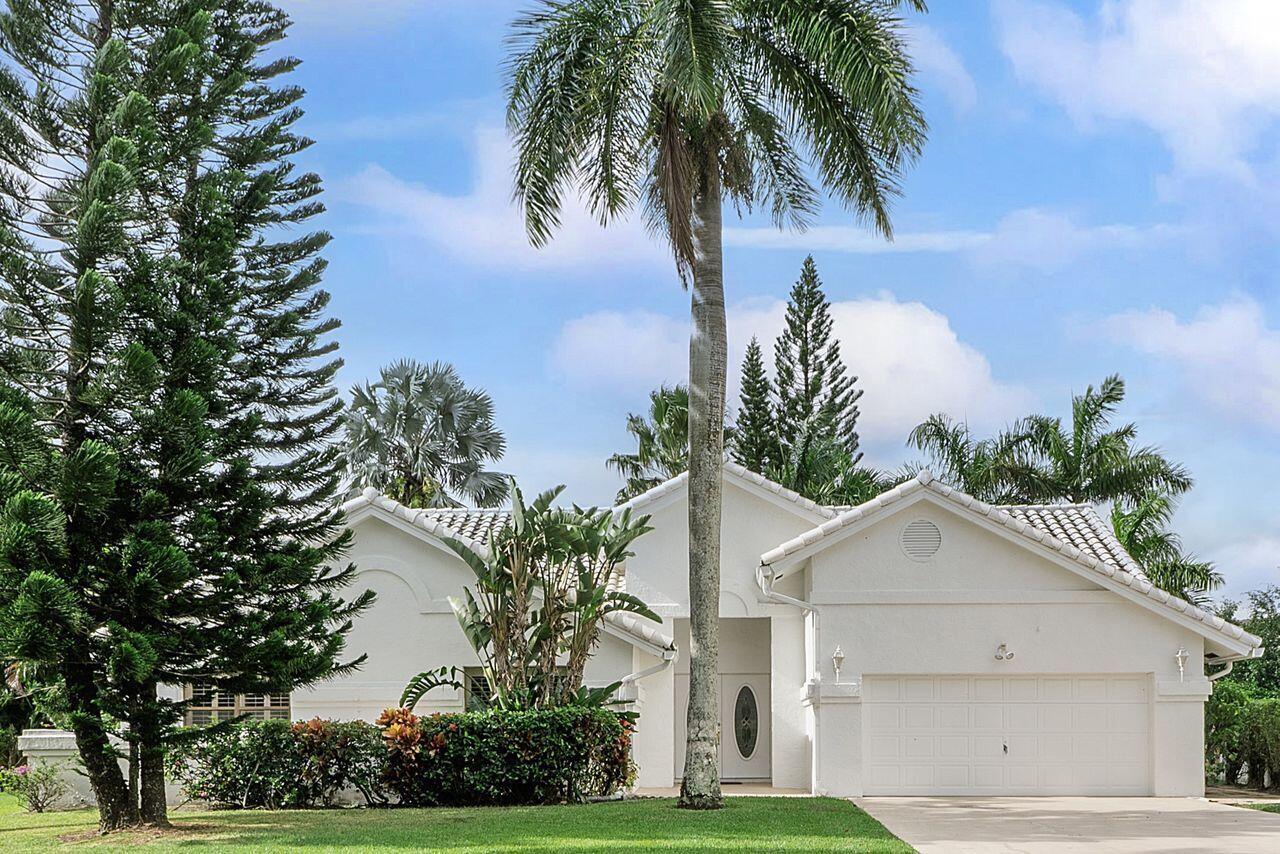 a view of a white house with a yard and palm trees