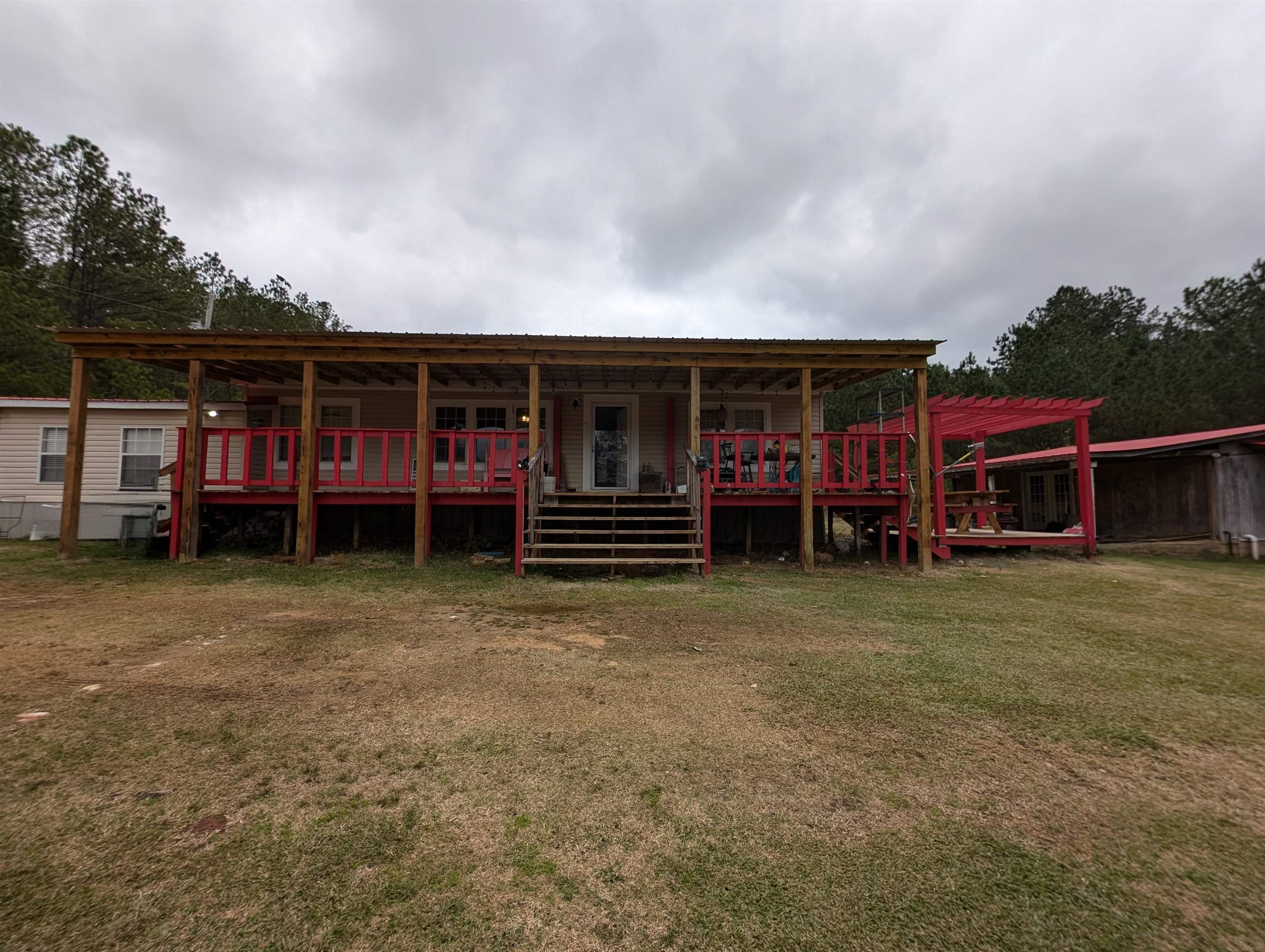 Back of house with a pergola and a lawn