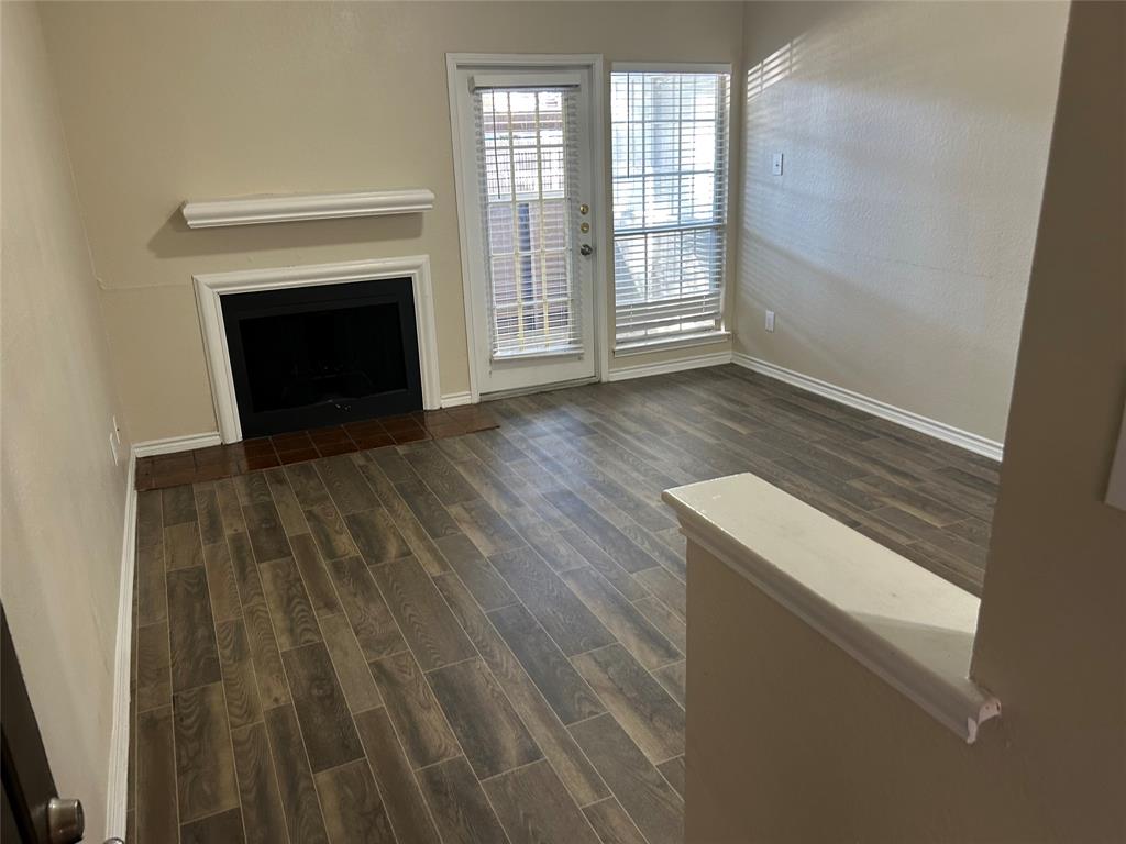 a view of empty room with wooden floor and fireplace