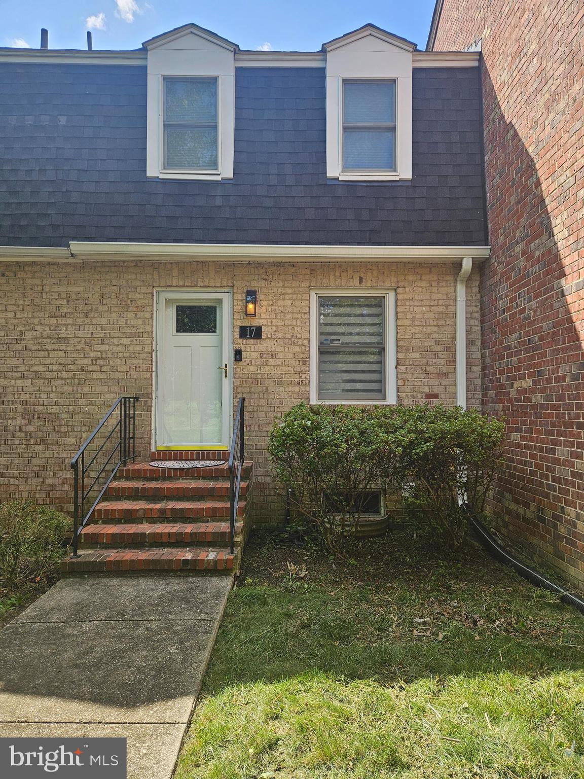 a view of a brick house with plants and a large tree