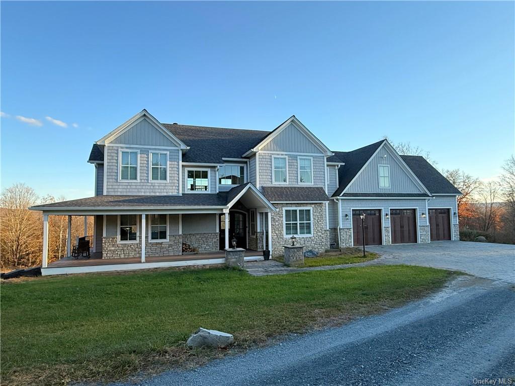 View of front of property with a front lawn, a garage, and covered porch