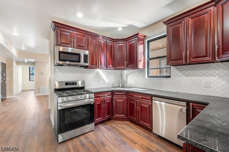 a kitchen with stainless steel appliances granite countertop wooden cabinets a stove a sink and a microwave