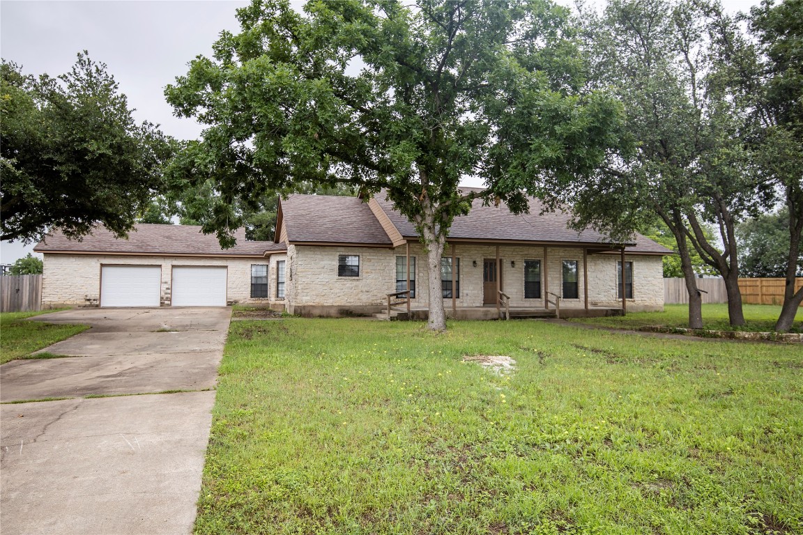 a front view of a house with a garden and trees