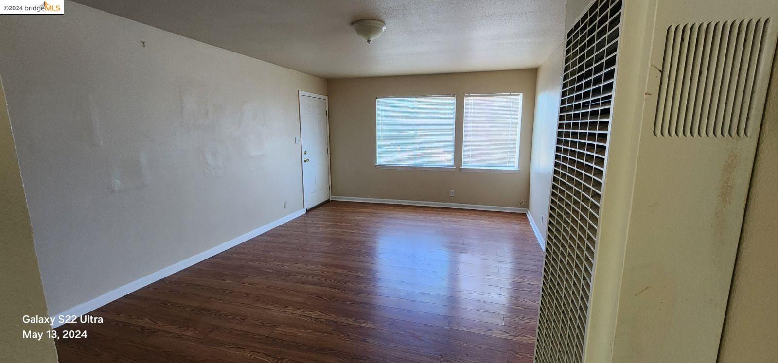 an empty room with wooden floor and windows