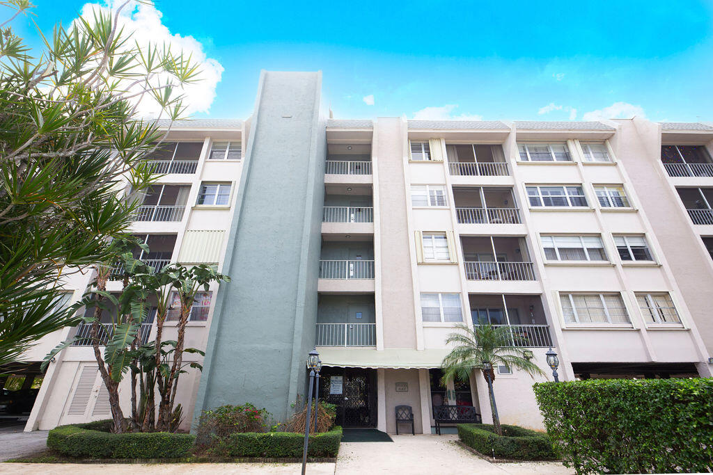 a front view of a multi story residential apartment building with yard and entryway