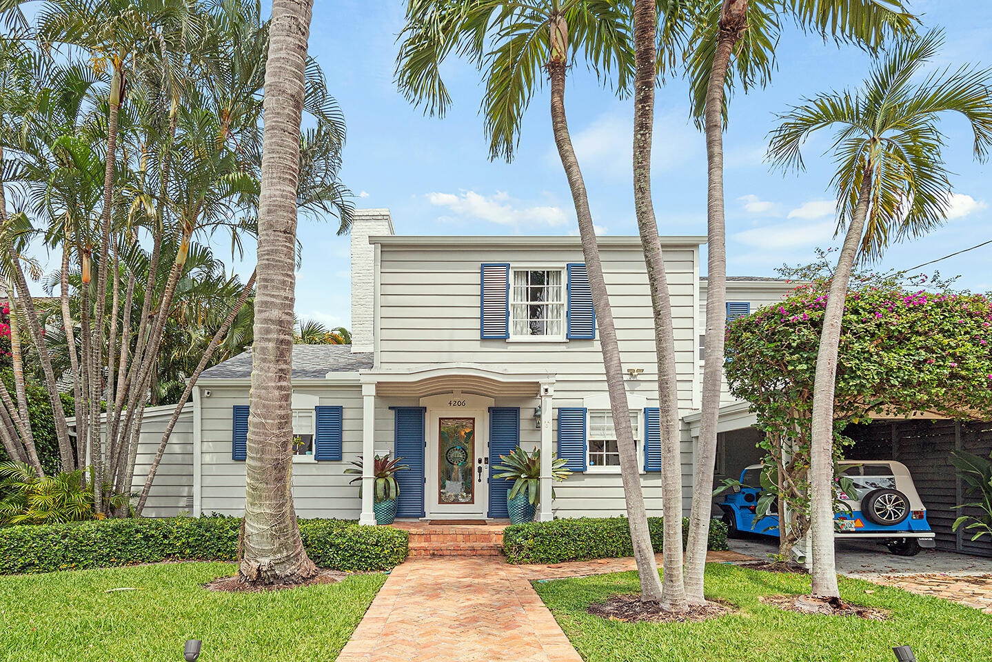 front view of house with a yard and palm trees