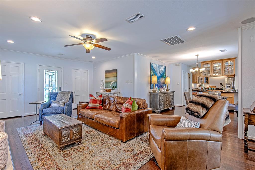 This view highlights the seamless flow from the living room into the dining area and kitchen, creating an open and inviting space perfect for entertaining. The rich hardwood floors, stylish decor, and ceiling fan add to the home's warmth and charm.