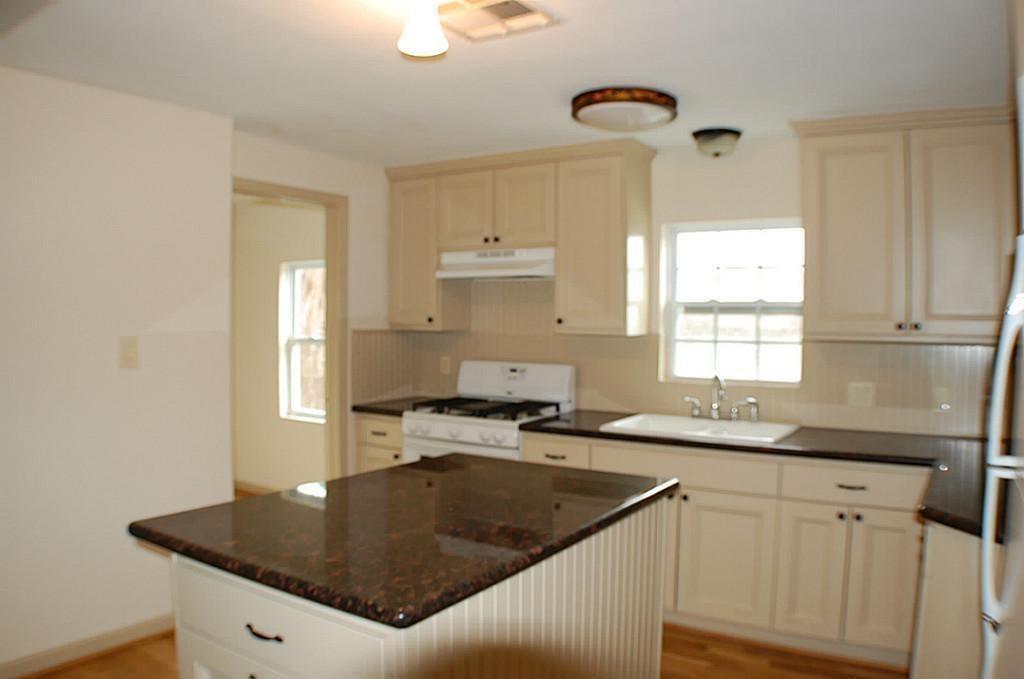 a kitchen with granite countertop a sink a window stainless steel appliances and cabinets