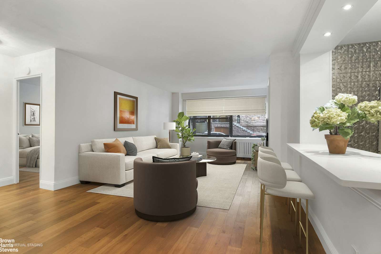 a living room with furniture a potted plant and a kitchen view