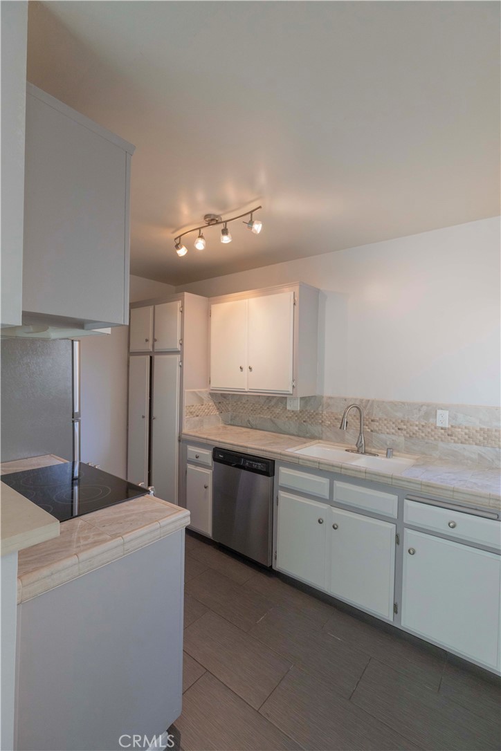 a large kitchen with a sink and dishwasher a stove with wooden floors