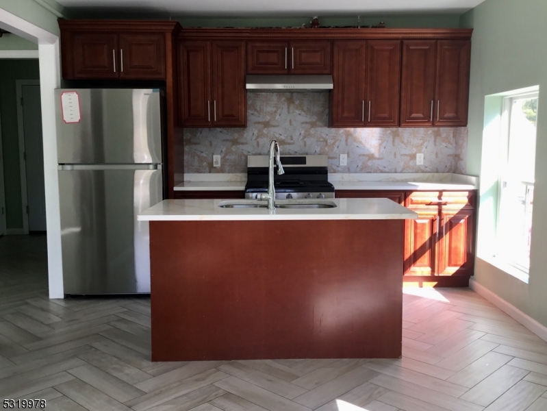 a kitchen with stainless steel appliances granite countertop a refrigerator a sink and wooden cabinets