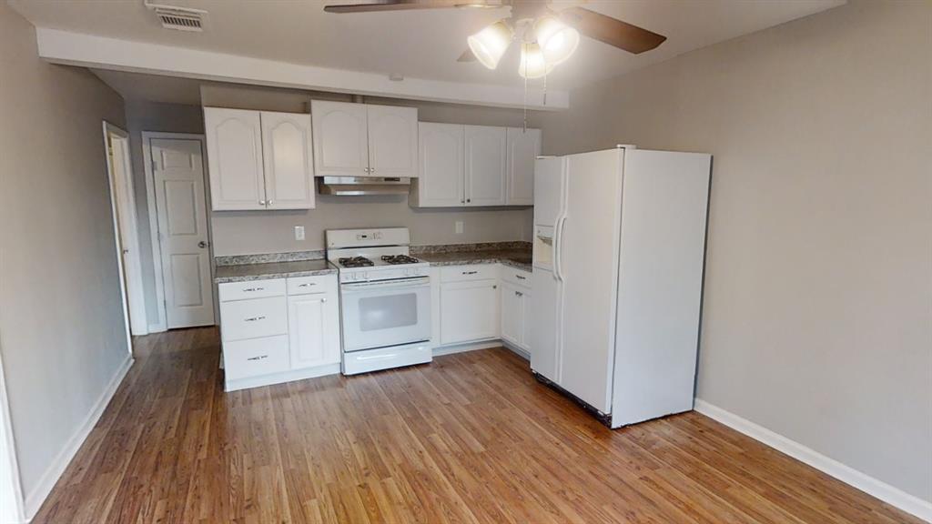 a kitchen with wooden floors and white appliances