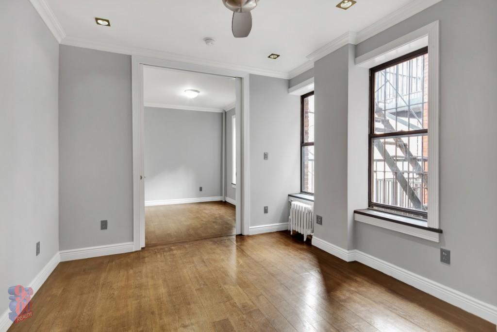 a view of an empty room with a window and wooden floor