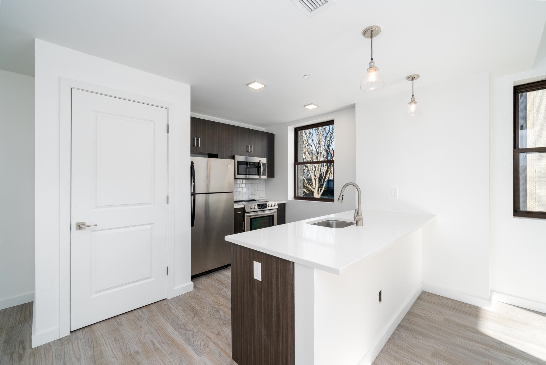 a kitchen with a sink a counter top space stainless steel appliances and wooden floor