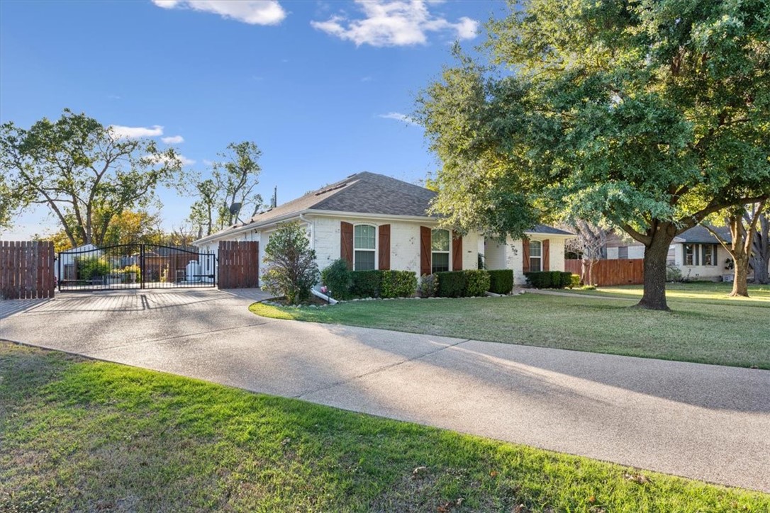 a view of a house with a yard and large tree