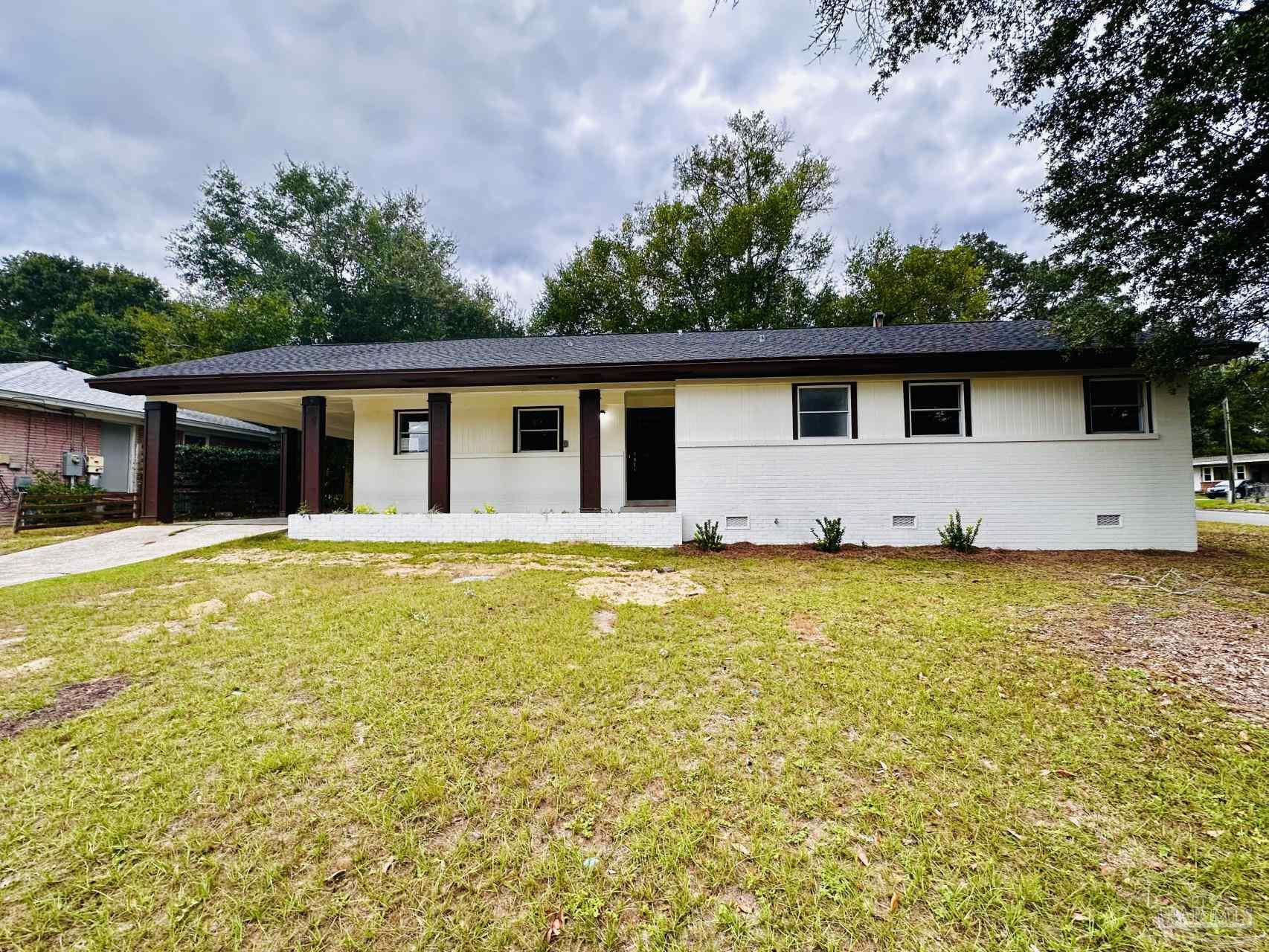 a front view of house with yard and trees in the background