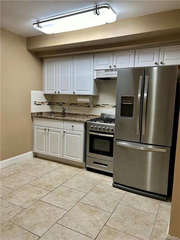 Kitchen featuring white cabinetry, stainless steel appliances, and decorative backsplash