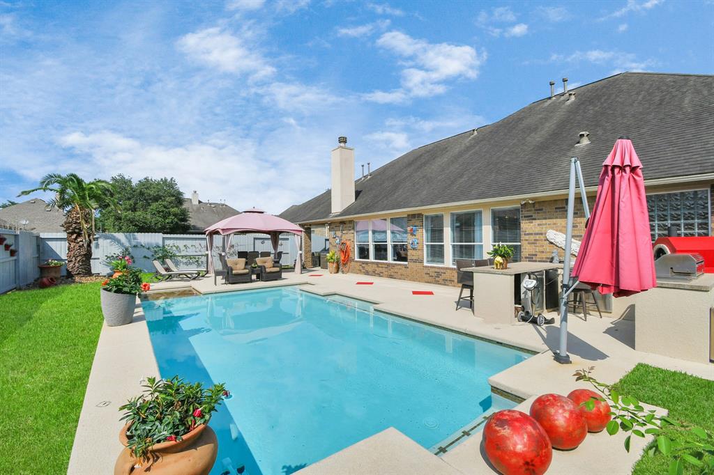 This expansive pool area is an entertainer's dream, featuring ample seating, a built-in barbecue, and a cozy gazebo. The lush landscaping and vibrant flowers create a serene atmosphere, while the crystal-clear pool invites you to take a refreshing dip. This outdoor space is perfect for hosting gatherings or enjoying quiet moments.