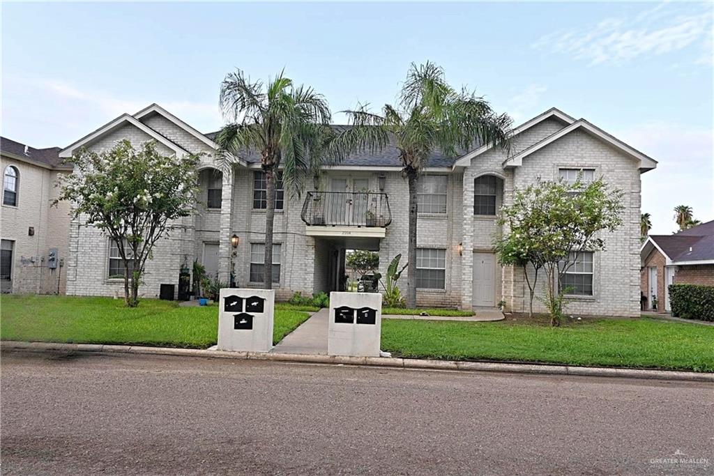 a front view of a house with a garden and trees