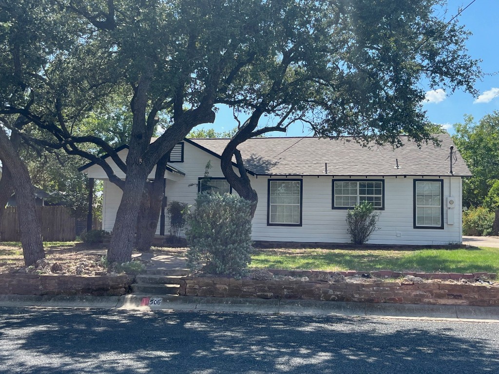 a front view of a house with a yard and large tree