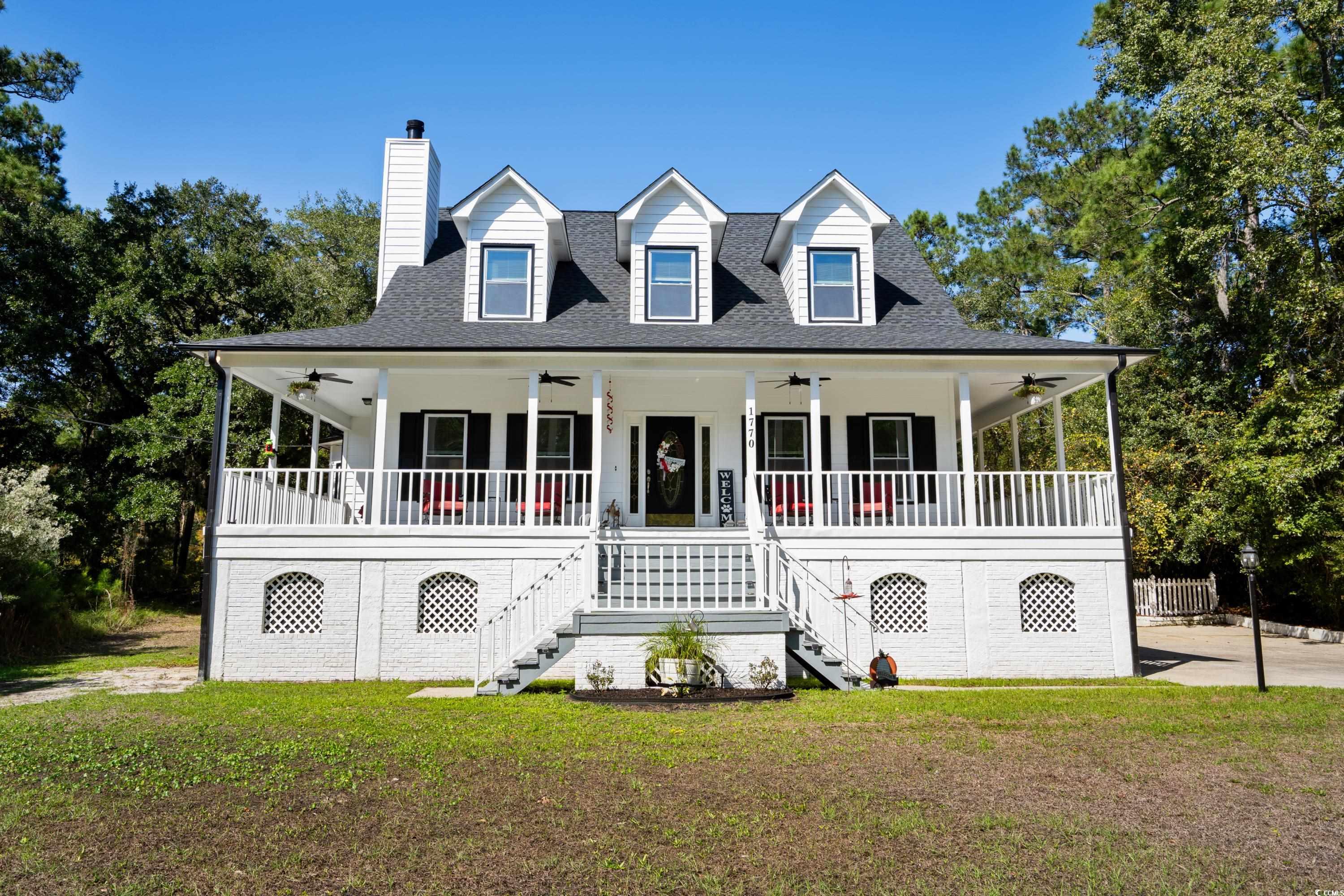 Country-style home with a front lawn and covered p