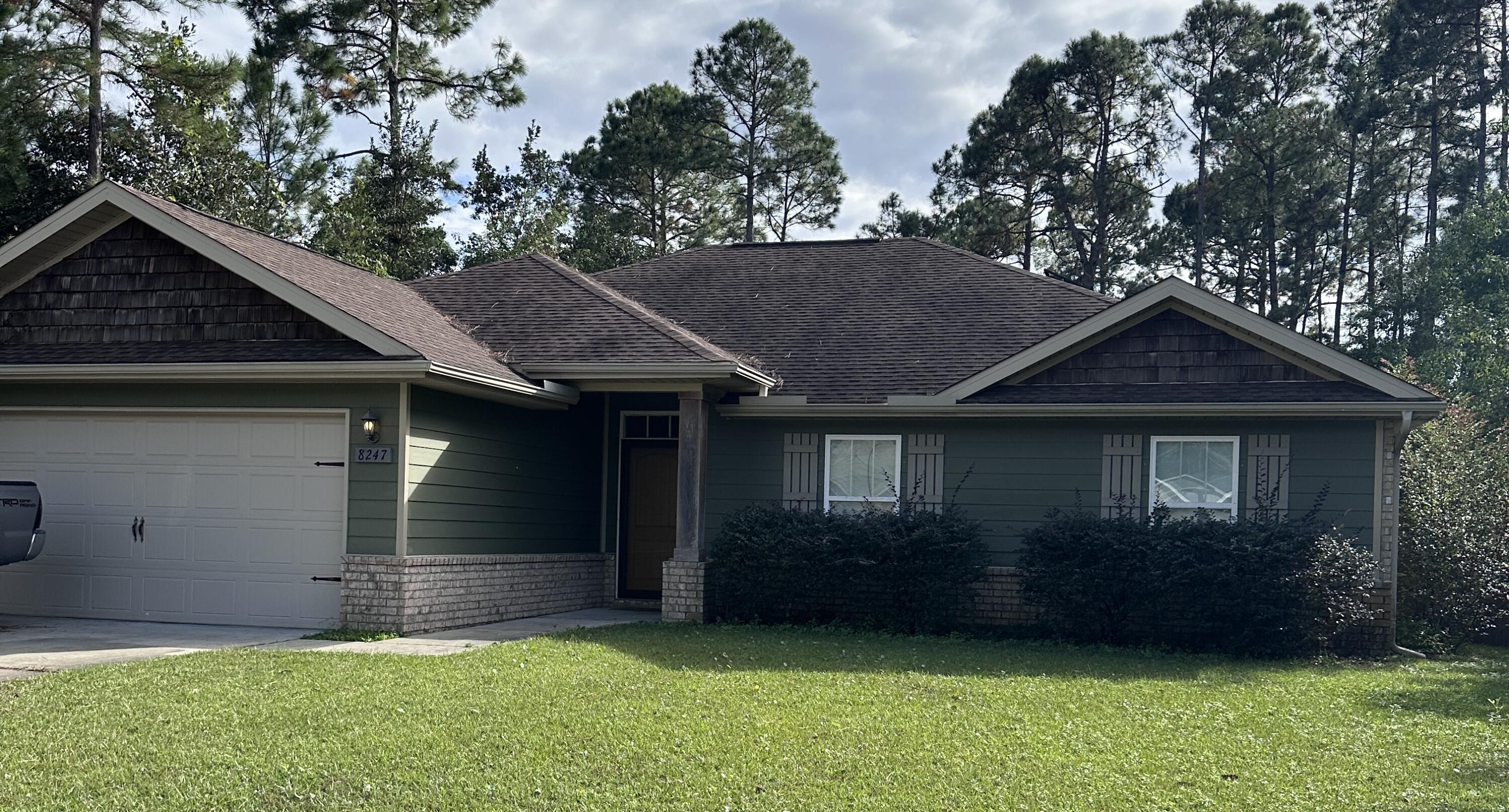 a view of a house with a yard plants and large tree