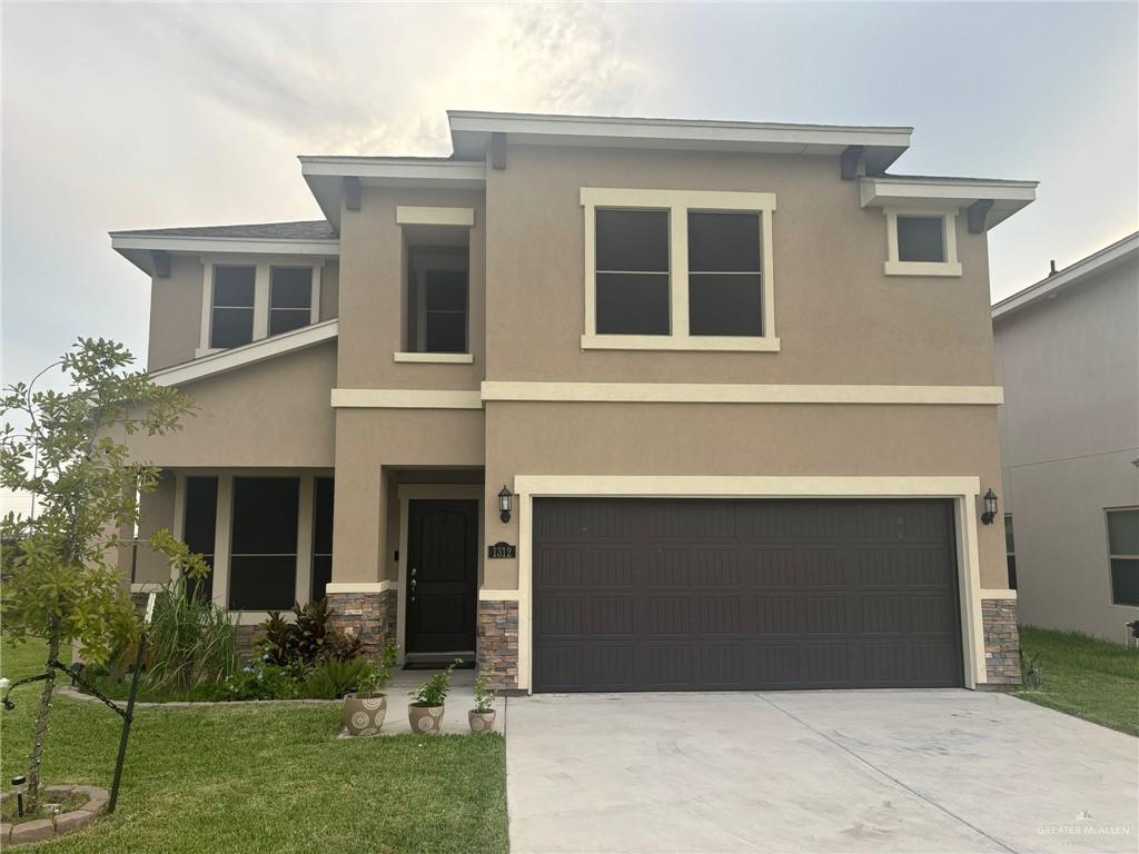 View of front of home with a garage and a front lawn