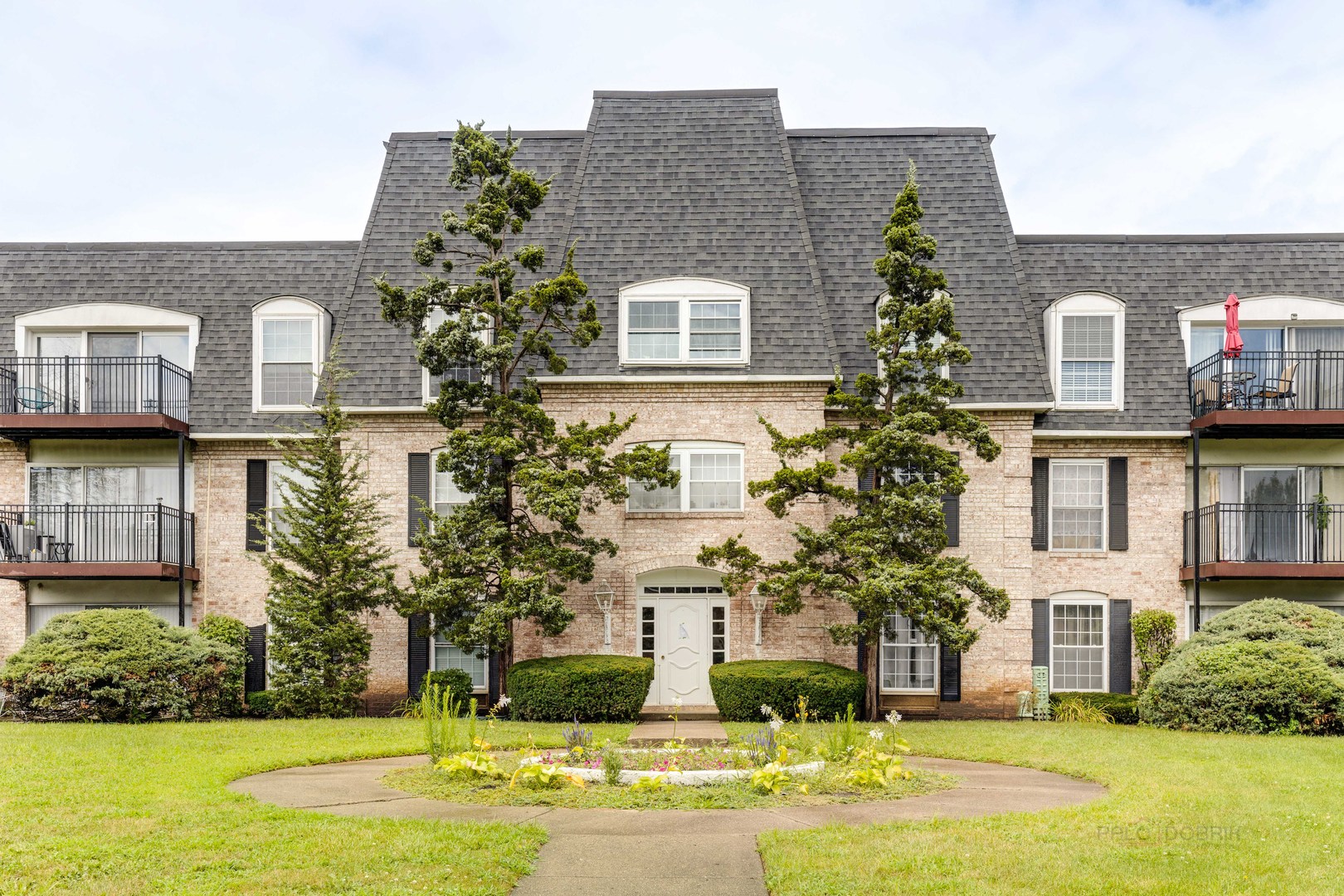 a front view of residential houses with yard and trees