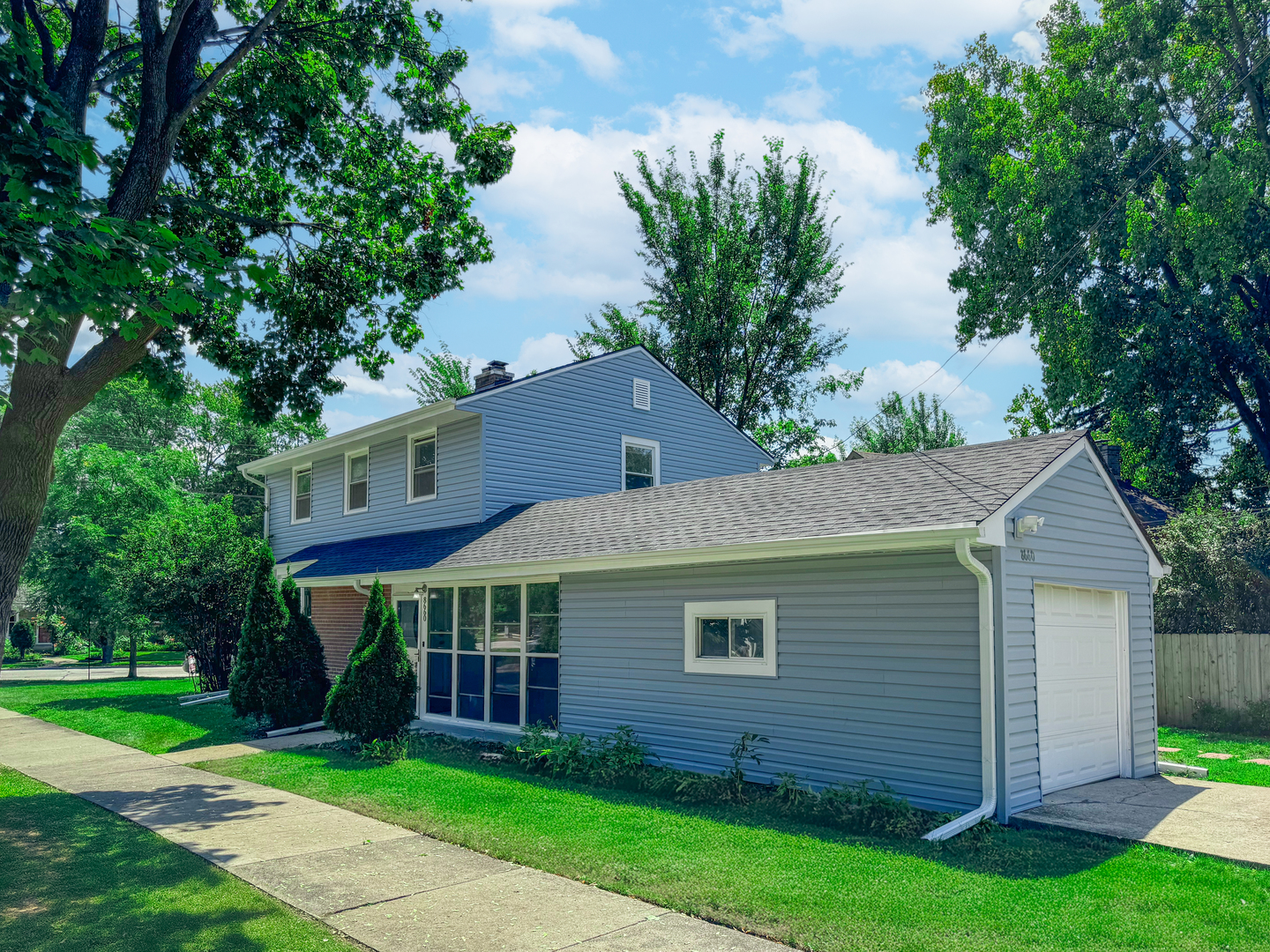 a aerial view of a house next to a yard and large trees