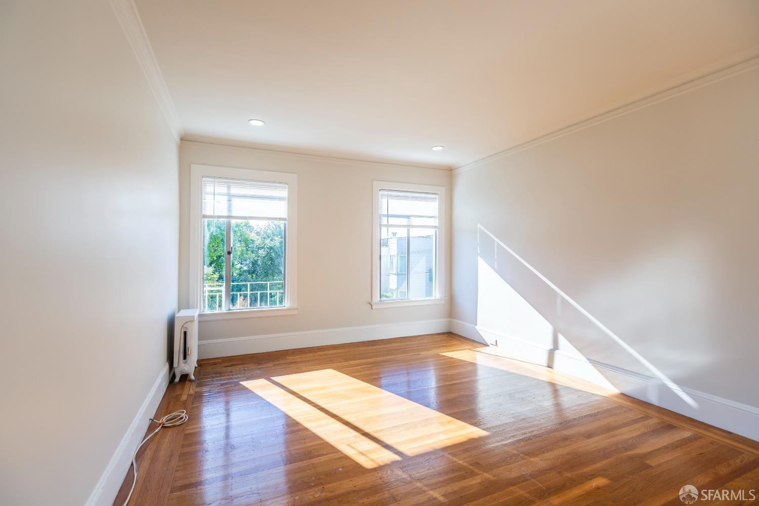 a view of an empty room with wooden floor and a window