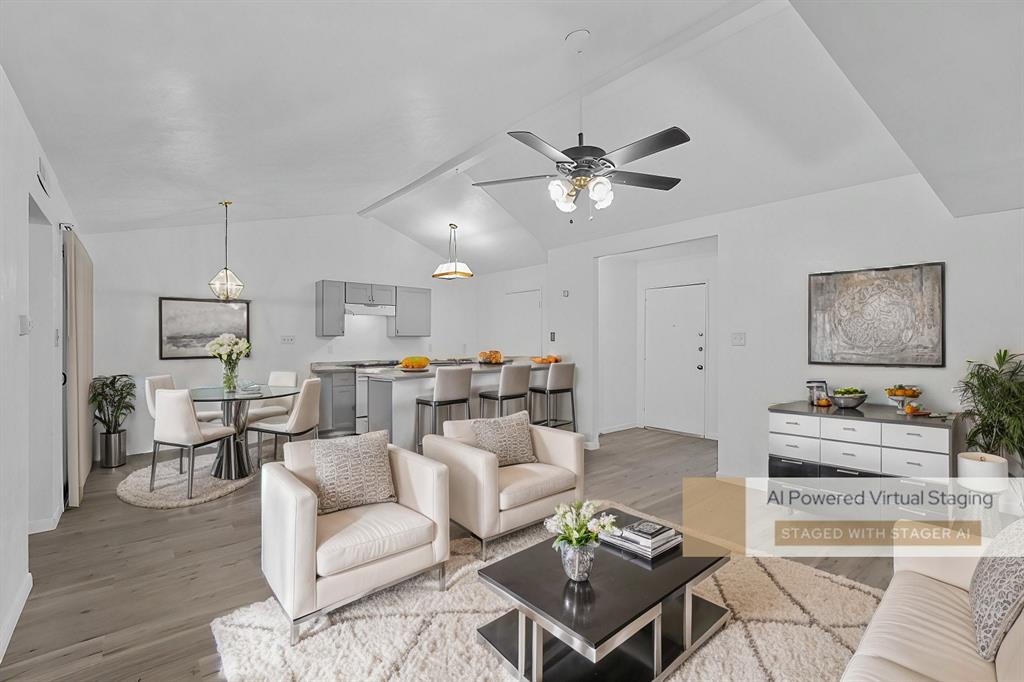 Living room with ceiling fan, light hardwood / wood-style floors, and vaulted ceiling