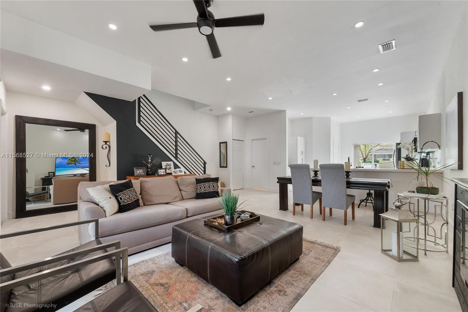 a living room with furniture kitchen view and a wooden floor