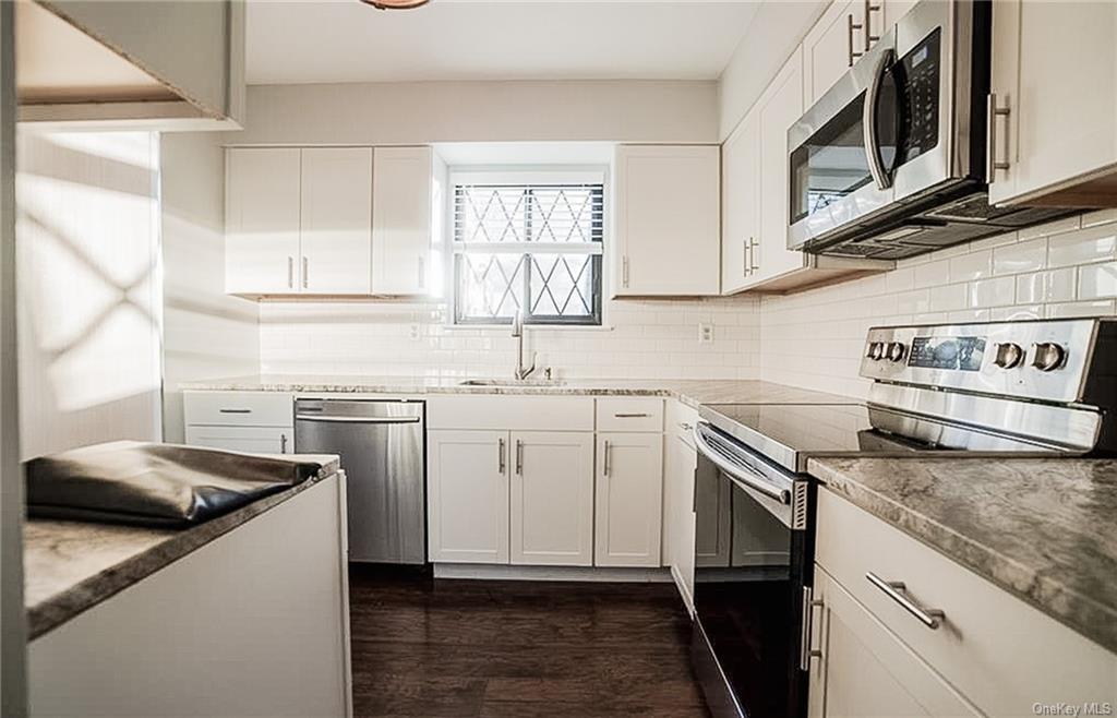 a kitchen with granite countertop cabinets stainless steel appliances and a window