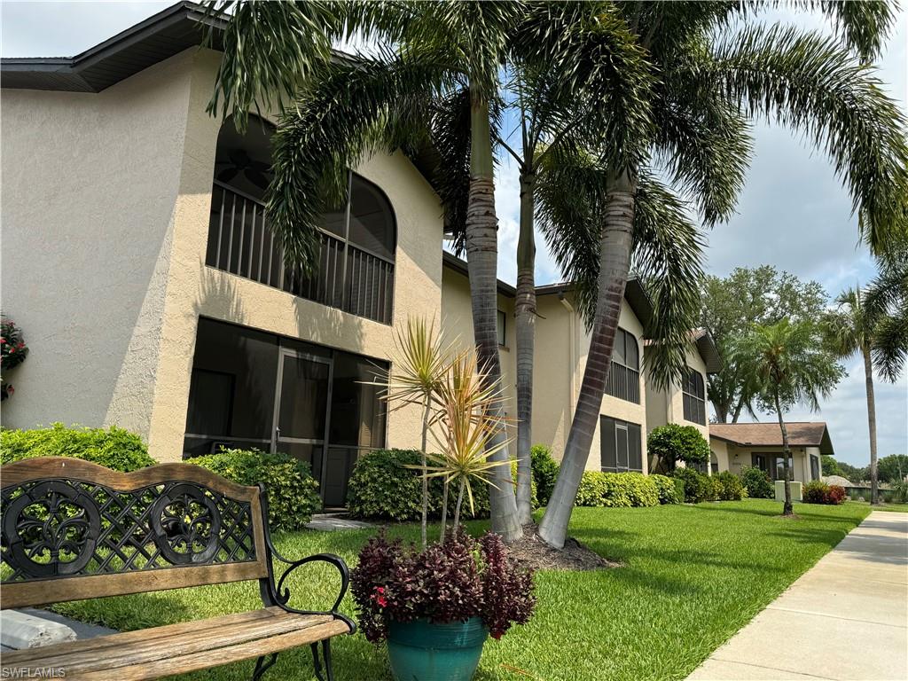 a view of a white house with a yard plants and palm trees