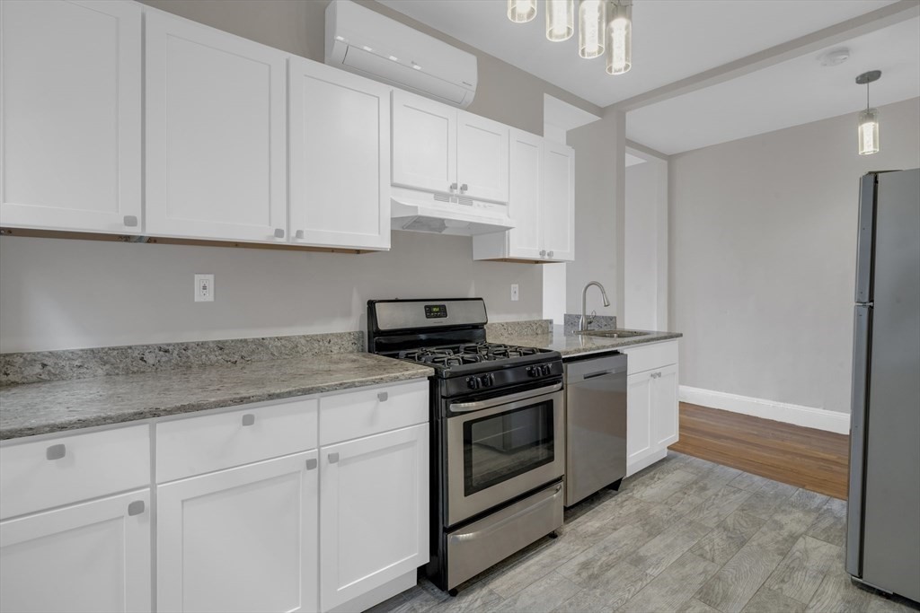 a kitchen with stainless steel appliances granite countertop white cabinets and a stove top oven