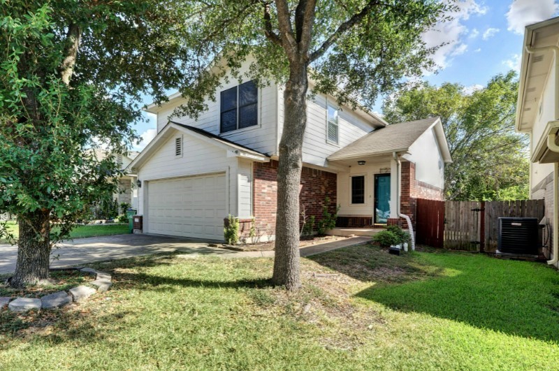 a view of a house with a yard and large tree