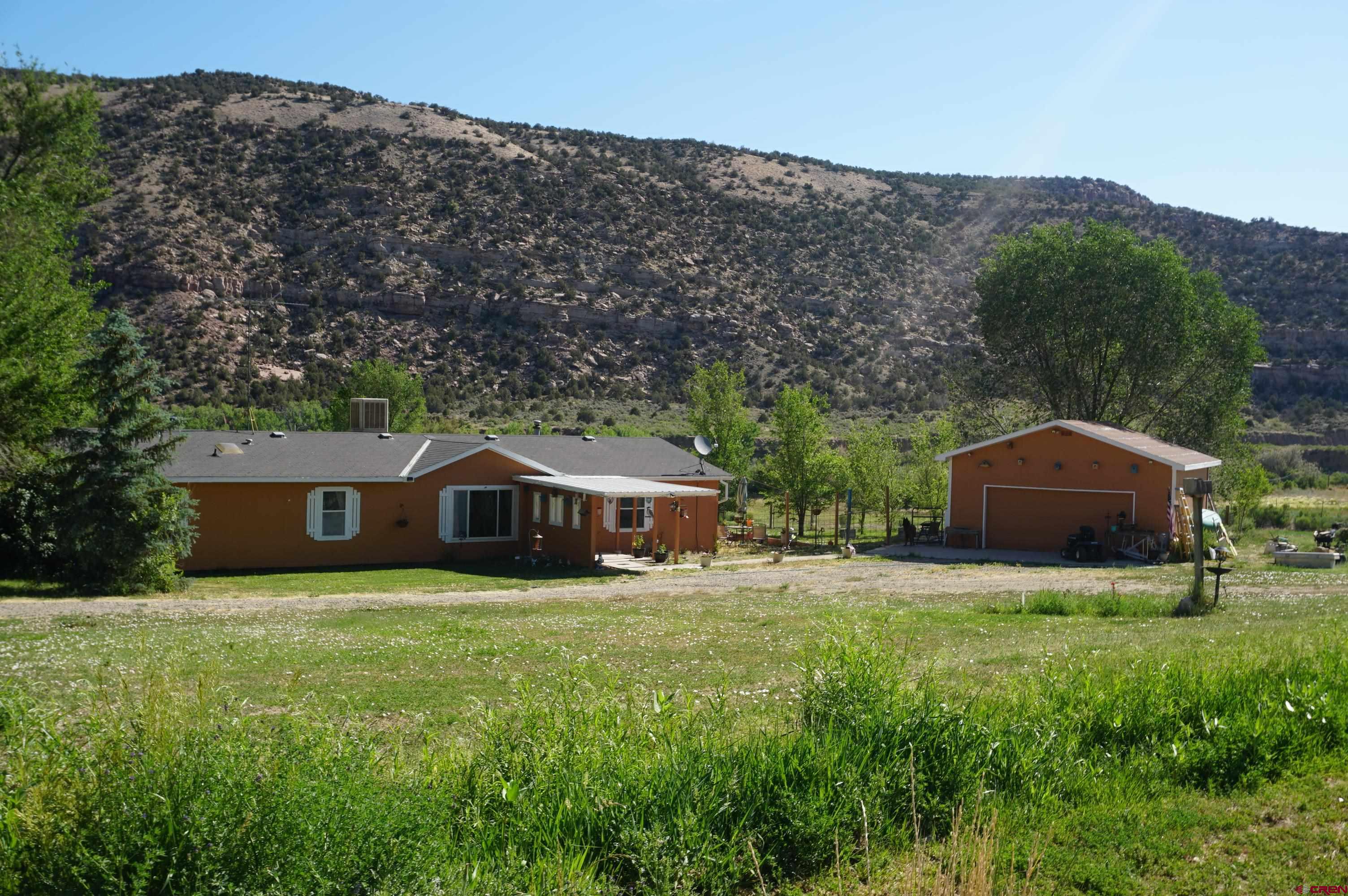 a view of a house with a yard and large trees