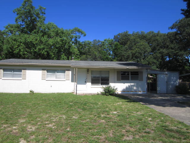 a front view of house with yard and trees in the background