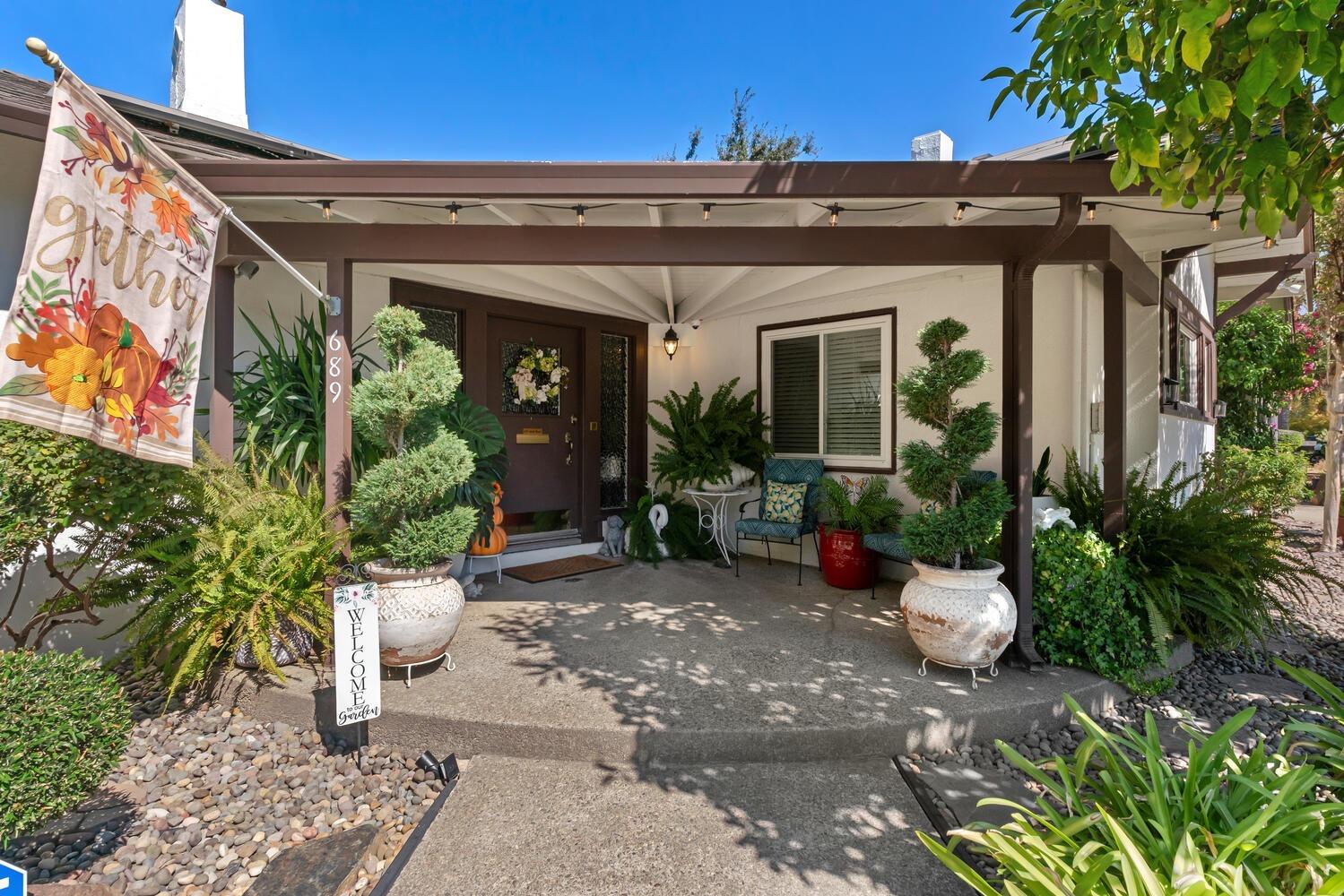 a view of a house with potted plants and a bench