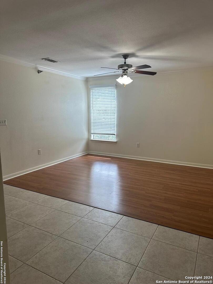 a view of empty room with wooden floor and fan