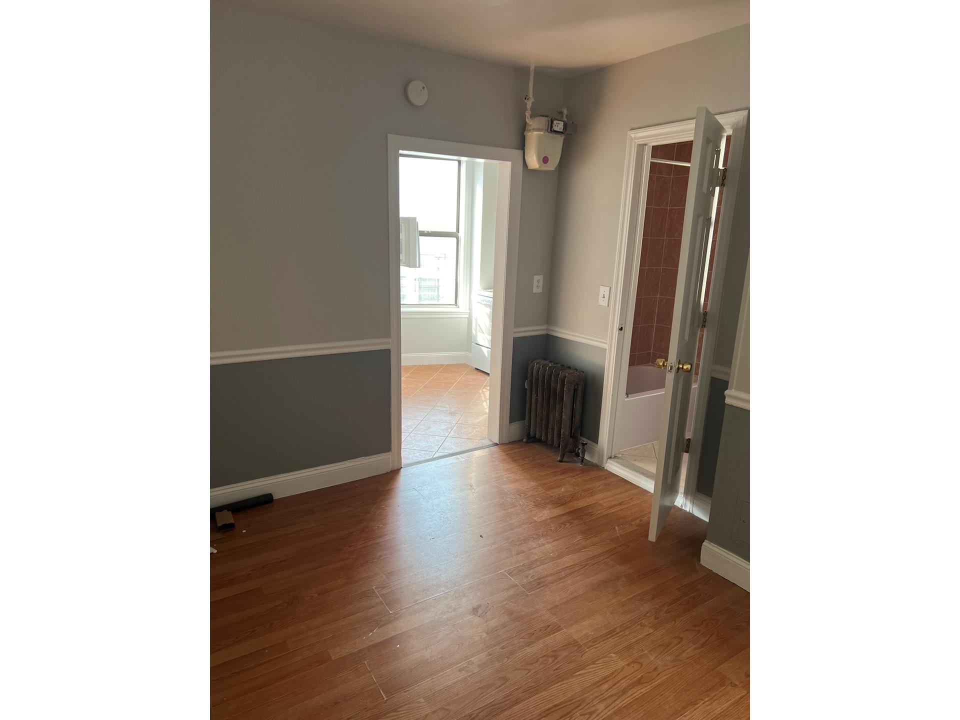 a view of a hallway with wooden floor and a bathroom