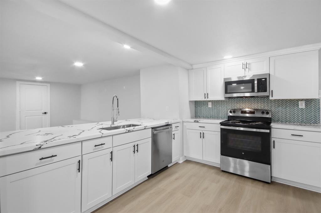 a kitchen with granite countertop white cabinets and stainless steel appliances