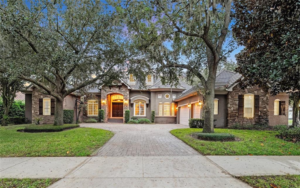 a front view of a house with a yard and large tree