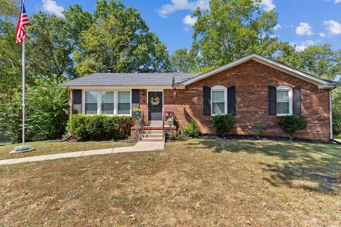 a view of a house with a yard and large tree